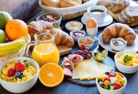 Colazione con croissant, frutta, uova e succo d'arancia.