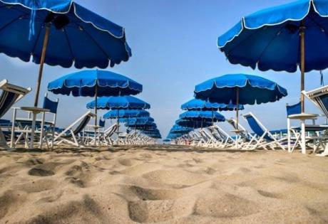 Spiaggia con ombrelloni blu e sedie a sdraio.