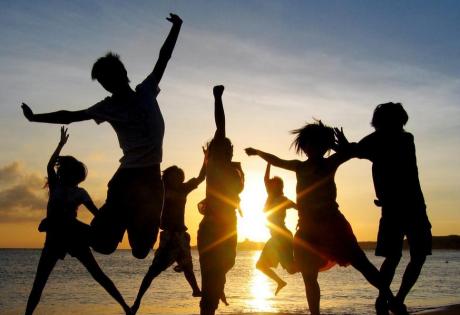 Persone saltano sulla spiaggia al tramonto.